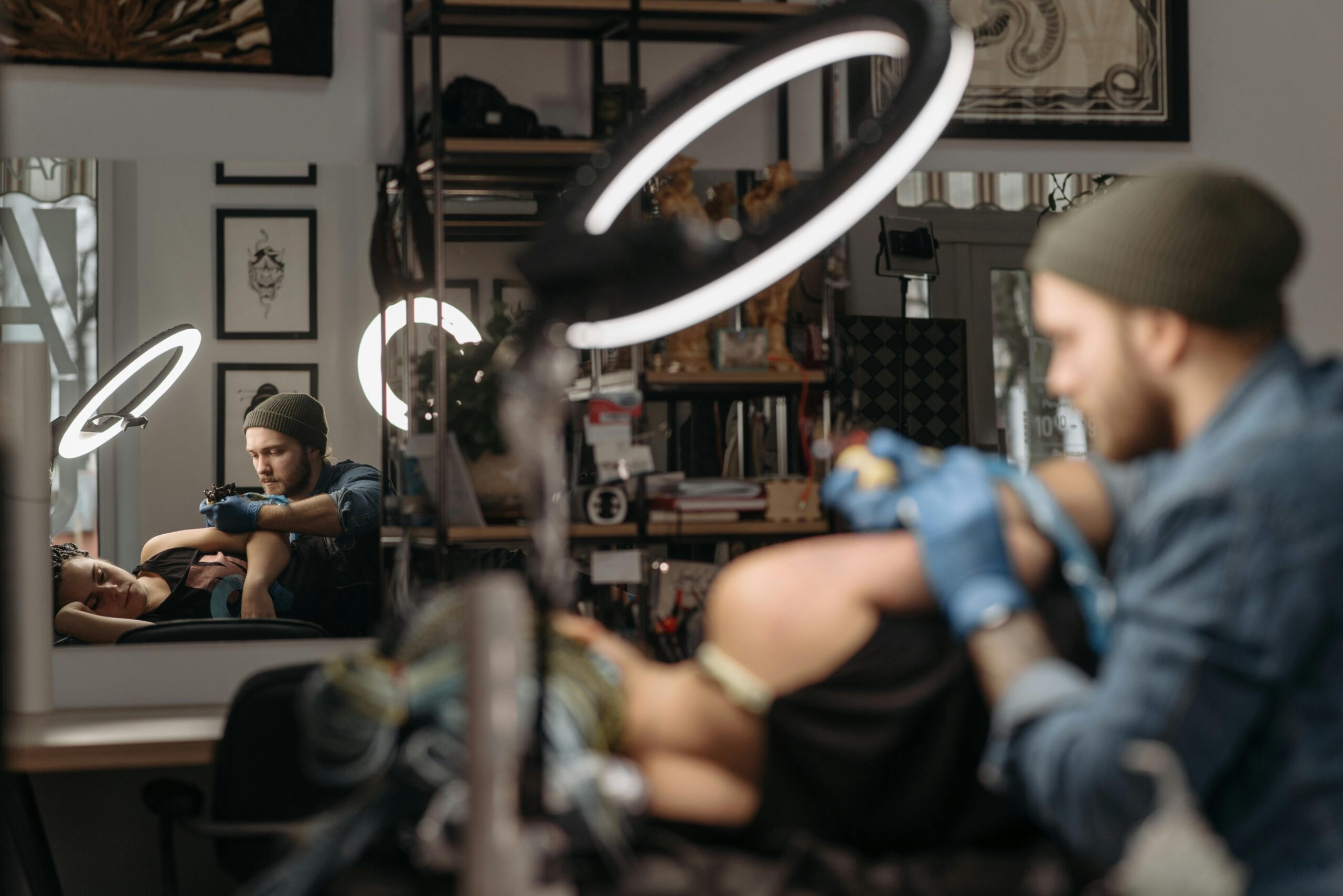 A tattoo artist focused on creating intricate designs in a well-lit tattoo studio.