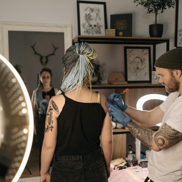Tattoo artist creating artwork on client's arm in a studio setting.